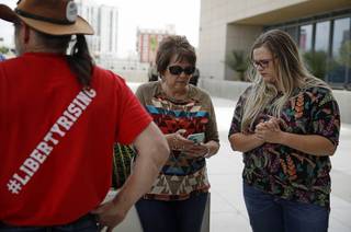 Carol Bundy, center, wife of Nevada rancher Cliven Bundy, looks at her phone beside Bailey Logue, daughter of Cliven Bundy, while waiting for a verdict outside of the federal courthouse, Monday, April 24, 2017, in Las Vegas. A jury found two men guilty of federal charges Monday in an armed standoff that stopped federal agents from rounding up cattle near Cliven Bundy's Nevada ranch in 2014. Jurors said they were deadlocked on charges against four other men, and the judge told them to keep deliberating.