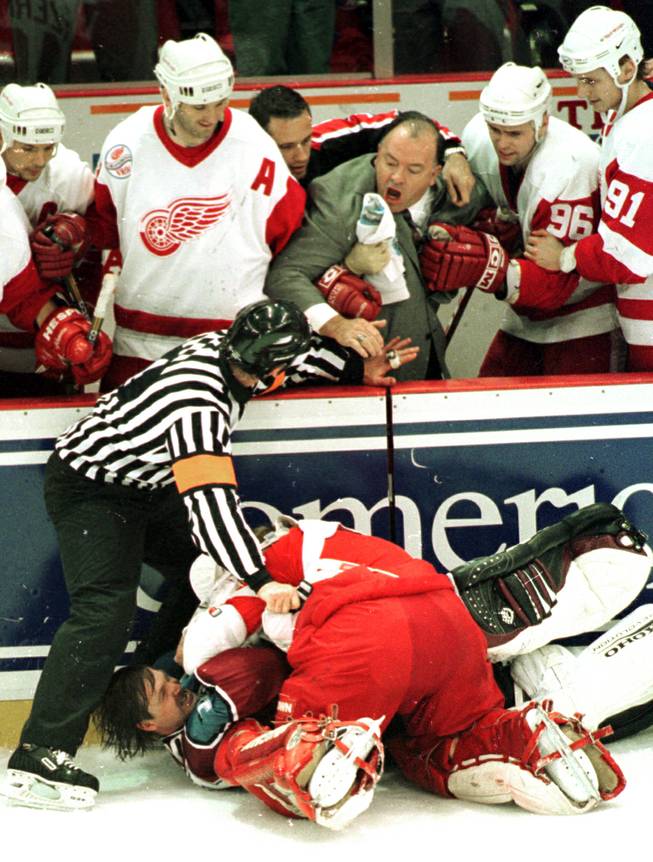 Referee Terry Gregson warns Detroit Red Wings coach Scotty Bowman to stay back as Wings goalie Chris Osgood and Colorado Avalanche goalie Patrick Roy fight in front of the Wings bench in the third period in Detroit, Wednesday, April 1, 1998. 