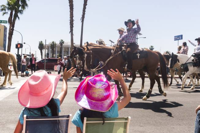 Two little girls wave at the passing horse riders during the Helldorado parade, Saturday, May 13, 2017.