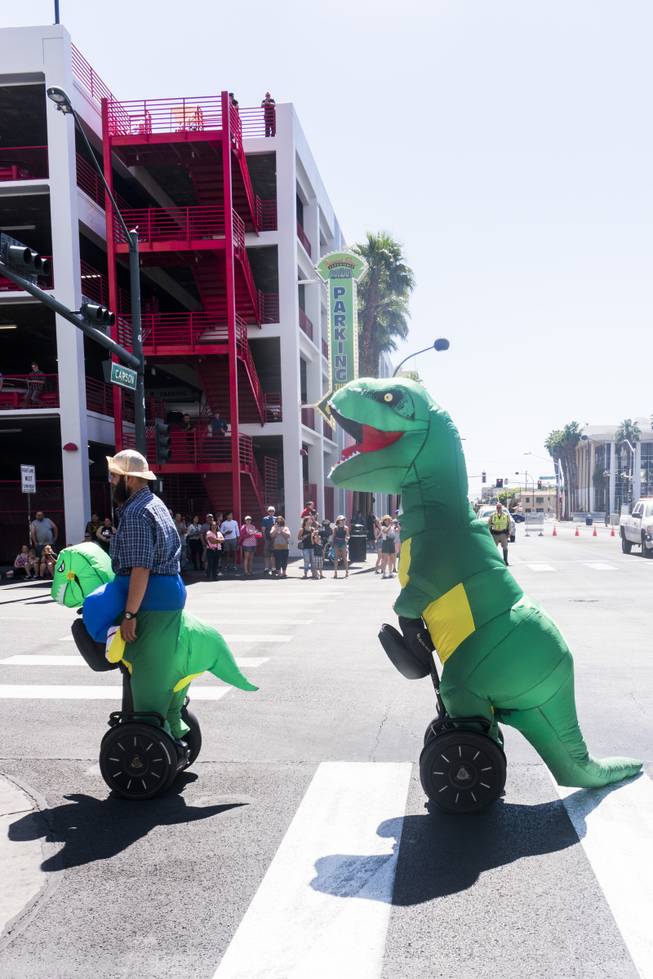 Two people in dinosaur costumes ride by on Segways during the Helldorado parade, Saturday, May 13, 2017.