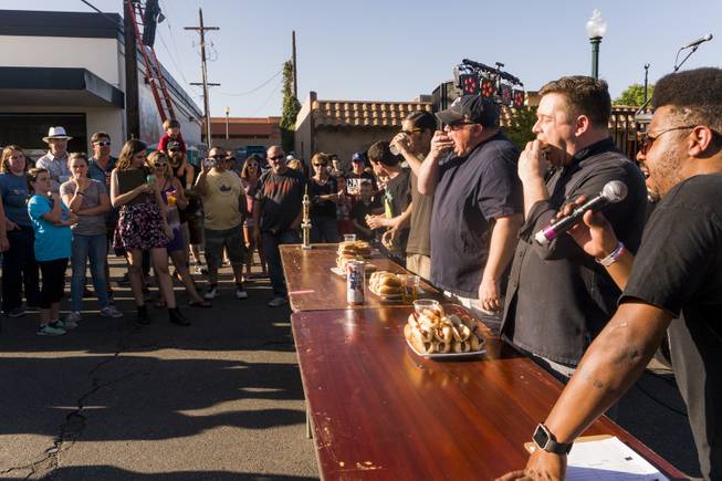A crowd watches as four competitors take their first bite of hotdog during the Teenie Weenie Hotdog Eating Contest at the annual Dillinger Block Party in Boulder City, NV, Saturday 13, 2017.