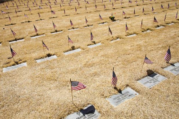 Flags stand over headstones during the Memorial Day Ceremony at the Southern Nevada Veterans Memorial Cemetery in Boulder City, NV, Monday, May 29, 2017. Large sections of grass at the Veterans Memorial Cemetery is being killed off for upcoming renovation efforts to raise the sinking headstone to ground level .