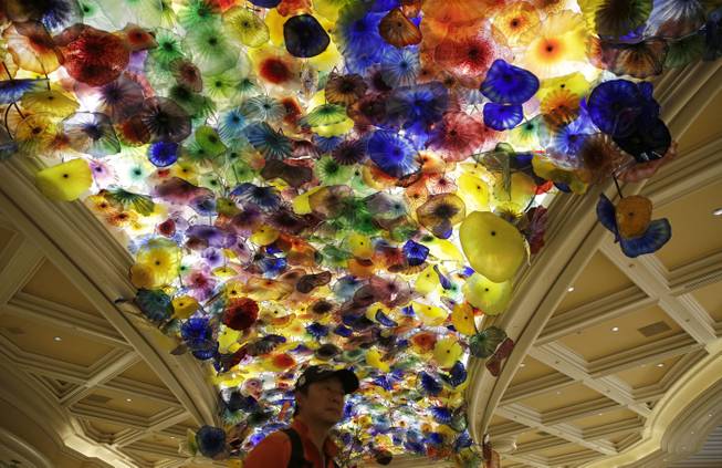A man stands beneath an installation by artist Dale Chihuly titled, "Fiori di Como," (Flowers of Como), suspended from the ceiling of the lobby at the Bellagio in Las Vegas.  (AP Photo/John Locher)