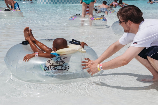 A chaperon helps a young boy float in a raft ...