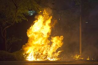 Bushes burn after a spark from fireworks ignited landscaping in a parking lot near Green Valley Parkway and I-215 in Henderson Tuesday, July 4, 2017.