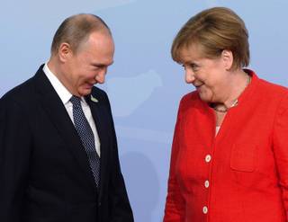 Russian President Vladimir Putin is greeted by German Chancellor Angela Merkel at the official welcoming ceremony at the G20 summit Friday, July 7, 2017 in Hamburg, Germany. (Remiorz/The Canadian Press via AP)