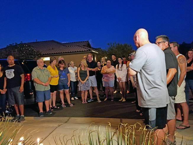 Neighbors gather for a vigil Tuesday, July 11, 2017, in front of a home in Mountain's Edge, where a day earlier the bodies of a man, woman and baby who died in an apparent murder-suicide were discovered. 