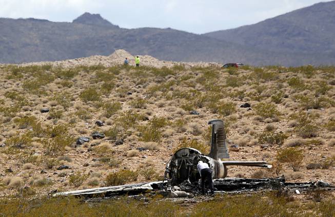 An investigator looks over the wreckage of a vintage single-engine British-built military jet after it crashed and burned in the desert just after takeoff from the Henderson Executive Airport in Henderson Monday, July 24, 2017. The pilot escaped serious injury, authorities said.