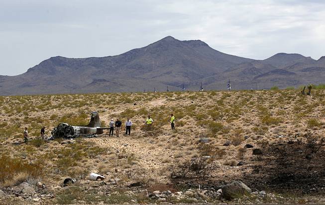 Officials look over a crash site after a vintage single-engine British-built military jet crashed and burned in the desert just after takeoff from the Henderson Executive Airport in Henderson Monday, July 24, 2017. The pilot escaped serious injury, authorities said.