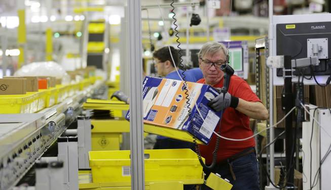 In this Monday, Nov. 30, 2015, file photo, Mark Oldenburg processes outgoing orders at Amazon.com's fulfillment center in DuPont, Wash.