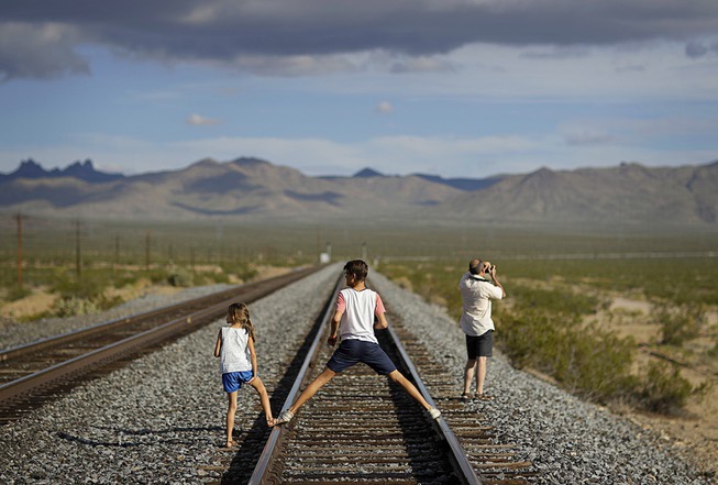 A family walks along train tracks, Thursday, Aug. 3, 2017, ...