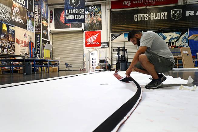 Gus Iniguez, production manager, looks over a concert banner at Screaming Images Wednesday, Aug. 16, 2017. The company is a graphic design, print and installation business.