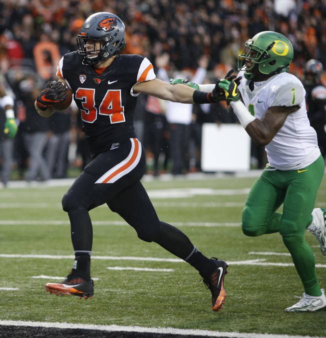 Oregon State running back Ryan Nall (34) stiff-arms his way past Oregon's Arrion Springs (1) for a touchdown in the second half an NCAA college football game in Corvallis, Ore., Saturday Nov. 26, 2016.