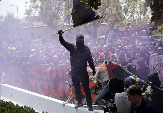 A masked left-wing demonstrator jumps over a barricade during a free speech rally Sunday, Aug. 27, 2017, in Berkeley, Calif. Several thousand people converged in Berkeley Sunday for a "Rally Against Hate" in response to a planned right-wing protest that raised concerns of violence and triggered a massive police presence. Several people were arrested for violating rules against covering their faces or carrying items banned by authorities. 