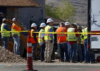 Construction workers look on as Henderson Firefighters retrieve the body of a worker from a manhole on Las Vegas Boulevard South near St. Rose Parkway, Sept. 25, 2017.