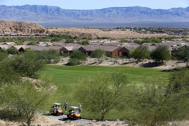 Golfers are shown on a course adjacent to the Prominance community, left, where mass shooter Stephen Craig Paddock owned a home, in Mesquite, Nev. Monday, Oct. 2, 2017.