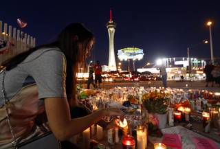 Dashenka Giraldo of Las Vegas lights candles at a makeshift memorial for shooting victims at the Las Vegas Strip and Sahara Avenue Wednesday, Oct. 4, 2017.