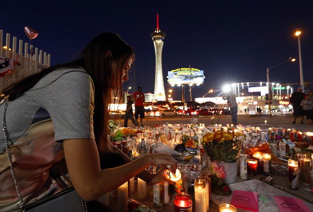 Dashenka Giraldo of Las Vegas lights candles at a makeshift memorial for shooting victims at the Las Vegas Strip and Sahara Avenue Wednesday, Oct. 4, 2017.