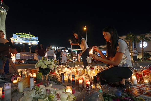 Elisabeth Apcar, center, and her cousin Dashenka Giraldo, both of Las Vegas, light candles at a makeshift memorial for shooting victims at the Las Vegas Strip and Sahara Avenue Wednesday, Oct. 4, 2017.