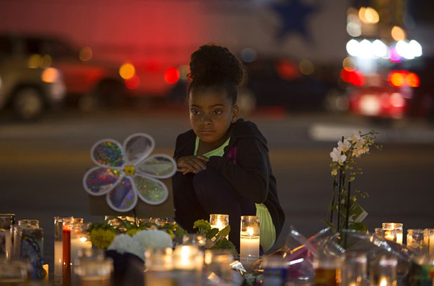 A girl looks over a makeshift memorial for shooting victims at the Las Vegas Strip and Sahara Avenue Wednesday, Oct. 4, 2017.