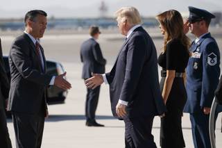 Nevada Gov. Brian Sandoval, left, greets President Donald Trump and first lady Melania Trump as they arrive Wednesday, Oct. 4, 2017, at Las Vegas McCarran International Airport to meet with victims and first responders of the mass shooting.