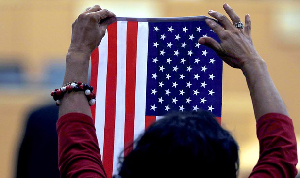 A woman holds up an American flag as U.S. Vice President Mike Pence speaks in Las Vegas City Hall following a Unity Prayer Walk Saturday, Oct. 7, 2017.
