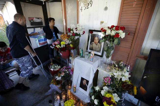 Angelica Silva, the mother of mass shooting victim and security guard Erick Silva, leads Jeff Bachman, a fellow security guard who was shot in the leg during last Sunday's mass shooting, past a candle-lit memorial with photos of Erick and flowers to honor him at his home Friday, Oct. 6, 2017, in Las Vegas.