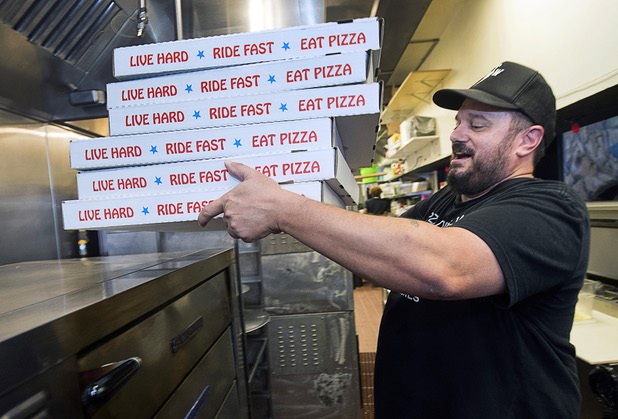 Owner Branden Powers lifts a stack of pizzas in the kitchen at Evel Pie, 508 E. Fremont St., in downtown Las Vegas Sunday, Oct. 8, 2017. The pizza shop, in collaboration with the Helpful Hoodlums charity group, is donating pizza and drinks to first responders in the wake of the Oct. 1 Route 91 Harvest festival mass shooting.