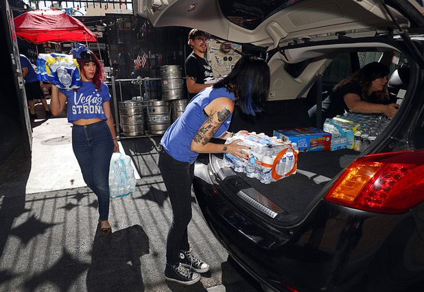 Volunteers Kitschy Koo, left, and Jess King, center, load drinks into a vehicle at Evel Pie, 508 E. Fremont St., in downtown Las Vegas Sunday, Oct. 8, 2017. The pizza shop, in collaboration with the Helpful Hoodlums charity group, is donating pizza and drinks to first responders in the wake of the Oct. 1 Route 91 Harvest festival mass shooting.
