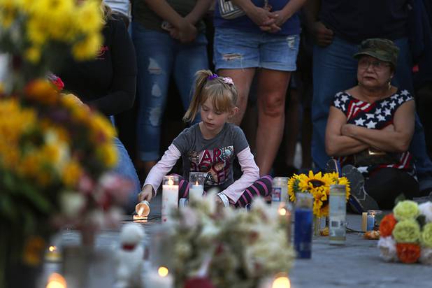 A girl lights a candle at a makeshift memorial during a vigil, marking the one-week anniversary of the Oct. 1 mass shooting, at Sahara Avenue and The Strip Sunday, Oct. 8, 2017.