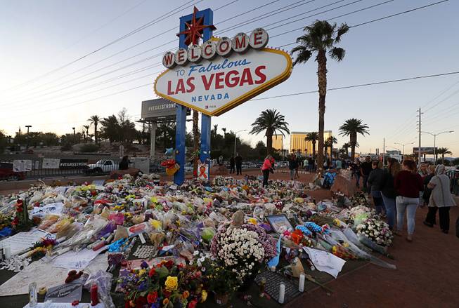 The Welcome to Las Vegas sign is surrounded by flowers and items, left after the Oct. 1 mass shooting, Monday, Oct. 9, 2017.