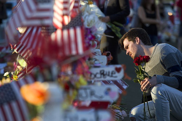 Taylor Perkins of Las Vegas looks over the wood cross for his friend Cameron Robinson, one of the 58 mass shooting victims, in the median of Las Vegas Boulevard South near the "Welcome to Las Vegas" sign Monday, Oct. 9, 2017.