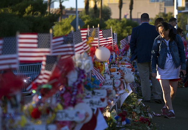Terri Xiang of Texas looks over 58 wood crosses, with the names and photos of the Oct. 1 mass shooting victims, in the median of Las Vegas Boulevard South near the "Welcome to Las Vegas" sign Monday, Oct. 9, 2017.