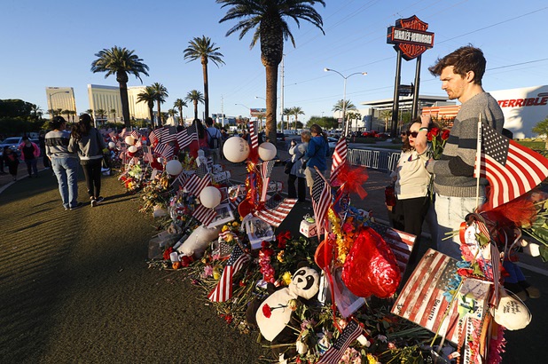 Taylor Perkins, right, a friend of shooting victim Cameron Robinson, stands by 58 wood crosses, with the names and photos of the Oct. 1 mass shooting victims, in the median of Las Vegas Boulevard South near the "Welcome to Las Vegas" sign Monday, Oct. 9, 2017.