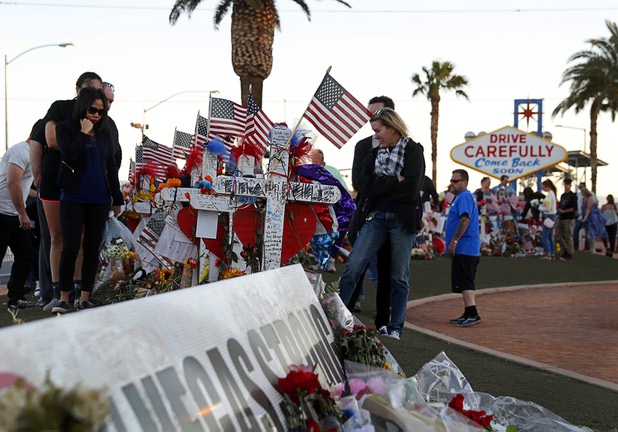 People look over 58 wood crosses, with the names and photos of the Oct. 1 mass shooting victims, in the median of Las Vegas Boulevard South near the "Welcome to Las Vegas" sign Monday, Oct. 9, 2017.