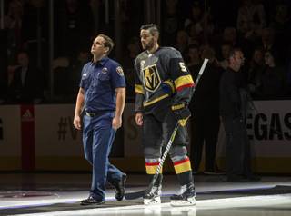 A first responder walks out onto the ice with Vegas Golden Knights defenseman Deryk Engelland (5) during opening ceremonies at their season home opener game at the T-Mobile Arena Tuesday, October 10, 2017.