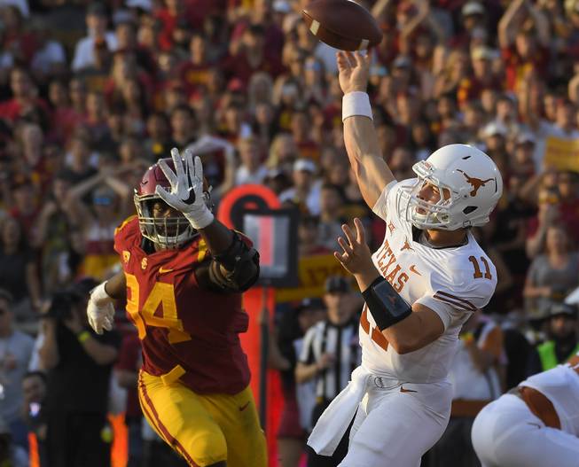 Texas quarterback Sam Ehlinger, right, passes as Southern California defensive tackle Rasheem Green defends during the first half of an NCAA college football game, Saturday, Sept. 16, 2017, in Los Angeles. 