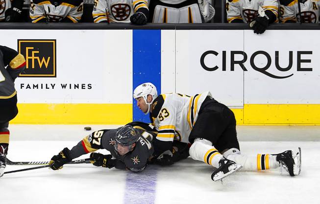 Vegas Golden Knights left wing David Perron (57) and Boston Bruins defenseman Zdeno Chara (33) slide across the ice during the first period at T-Mobile Arena Sunday, Oct. 15, 2017. Chara was penalized for slashing. 