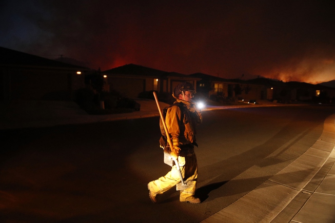 A firefighter looks for flammable items in an evacuated residential ...