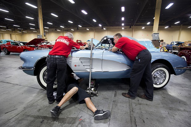 Tito De La Pena, bottom, of Mesa, Ariz. works to free a stuck hood latch on a 1959 Chevrolet Corvette before the 10th annual Barrett-Jackson Las Vegas classic car auction at the Mandalay Bay Convention Center Wednesday, Oct. 18, 2017. The three-day auction begins Thursday.