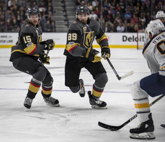 Vegas Golden Knights defenseman Jon Merrill (15) and Vegas Golden Knights right wing Alex Tuch (89) chase down a puck controlled by Buffalo Sabres center Ryan O'Reilly (90) during their game at the T-Mobile Arena on Tuesday, Oct. 17, 2017.