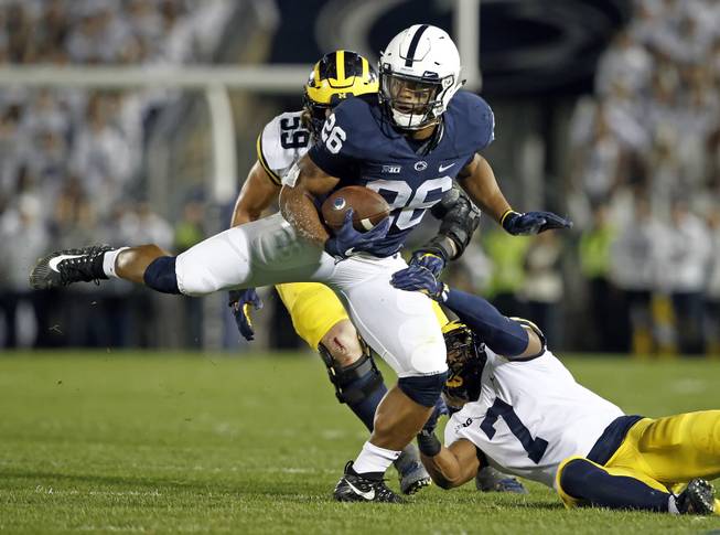 In this Saturday, Oct. 21, 2017, file photo, Penn State's Saquon Barkley (26) makes a move on Michigan's Khaleke Hudson (7) during the first half of an NCAA college football game in State College, Pa. Barkley has run roughshod over Big Ten defenses this year.