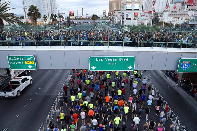 People watch runners from a pedestrian bridge at the start ...