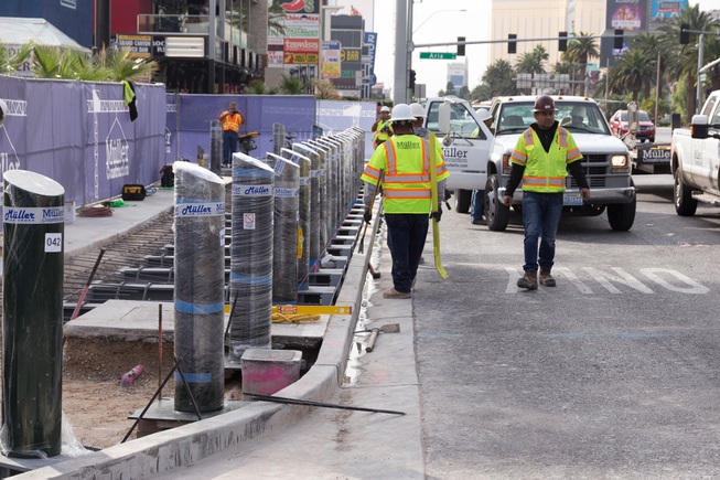 Construction workers install bollards along the Strip sidewalk in front ...