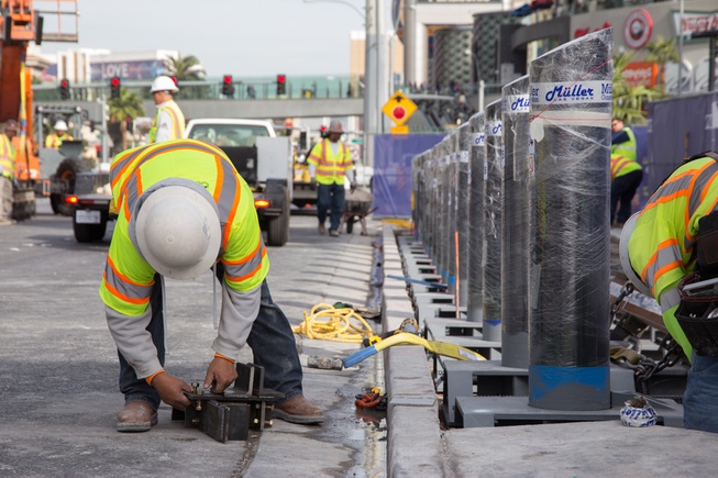 Construction workers install bollards along the Strip sidewalk in front ...