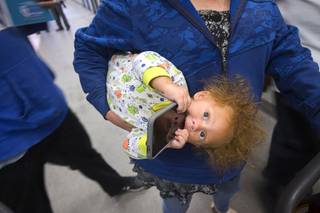 Katara James, 10 months, plays with her father's phone during Project Homeless Connect, an annual service and resource fair for at-risk and homeless people, at Cashman Field Center Tuesday, Nov. 14, 2017.