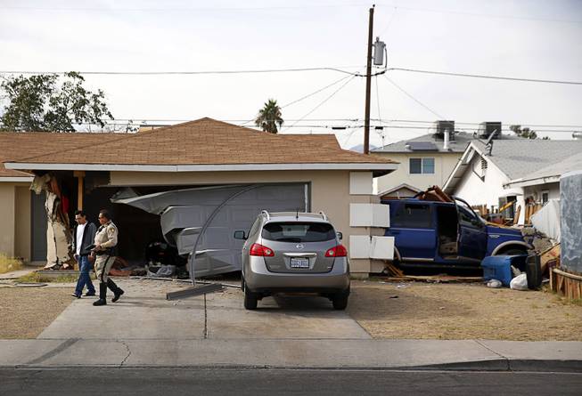 Resident Filipe Linares talks with a Metro Police office after a Ford Expedition SUV crashed into his home near Washington Avenue and Torrey Pines Drive Monday morning, Nov. 20, 2017.