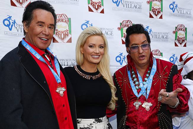Wayne Newton, honorary chairman, and Holly Madison, race grand marshal, pose Elvis tribute artist Jesse Garon during the 13th annual Las Vegas Great Santa Run in downtown Las Vegas Saturday Dec. 2, 2017. More than 9,000 runners registered for the event, according to organizers. The annual run is a fundraiser for Opportunity Village.