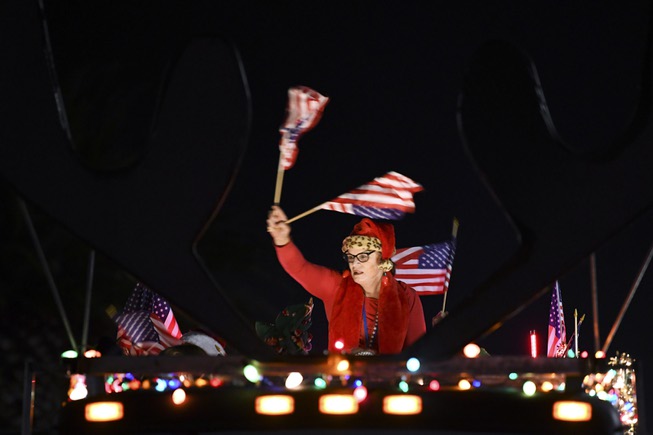 A woman waves United States flags during the Santa's Electric ...
