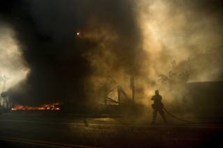 A firefighter tries to keep flames from spreading while battling a wildfire in Ventura, Calif., on Tuesday, Dec. 5, 2017. (AP Photo/Noah Berger)